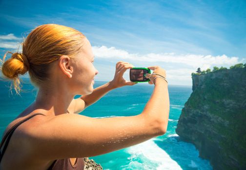 Tourist taking photo of Uluwatu temple, Bali, Indonesia