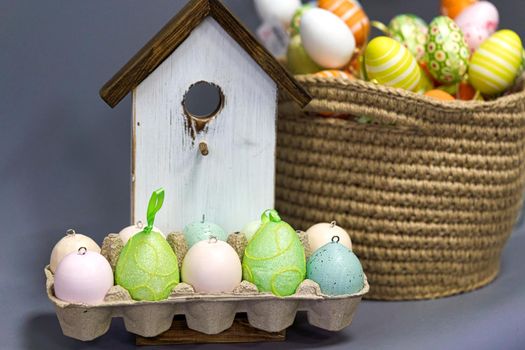 Multicolored easter eggs on the background of a wooden bird house. Close up