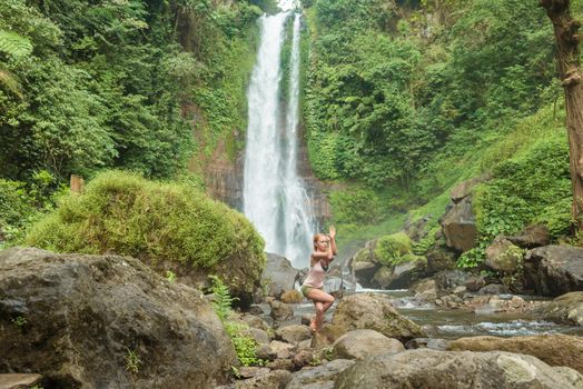 Young woman practicing yoga with waterfall in the background