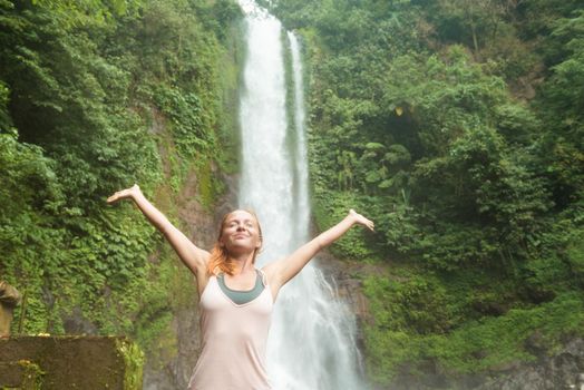 Young woman practicing yoga with waterfall in the background