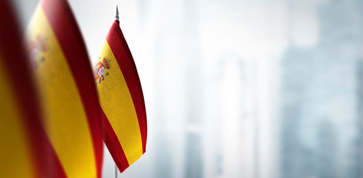 Small flags of Spain on a blurry background of the city.