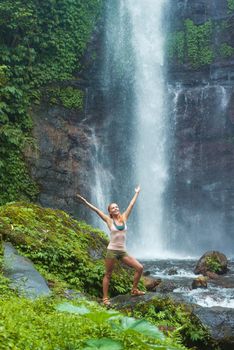 Young woman practicing yoga with waterfall in the background