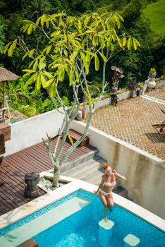 Young woman wearing swimsuit relaxing near swimming pool at exotic location