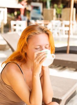 Young woman drinking coffee at beach in the morning