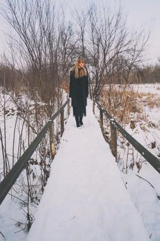 Lonely woman walking in park in winter.