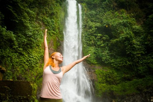 Young woman practicing yoga with waterfall in the background