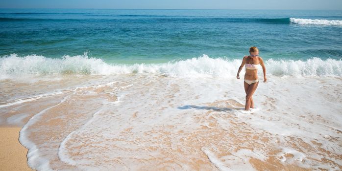 Young slim woman wearing bikini and sunglasses at the ocean beach