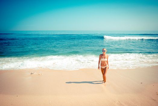 Young slim woman wearing bikini and sunglasses at the ocean beach