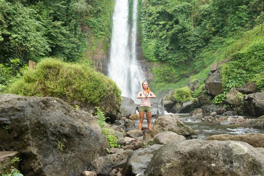 Young woman practicing yoga with waterfall in the background