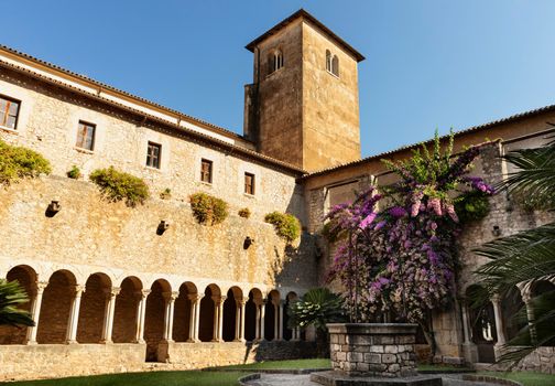 Cistercian Valvisciolo Abbey near Sermoneta ,part of medieval cloister  with well and purple bougainville in bloom
