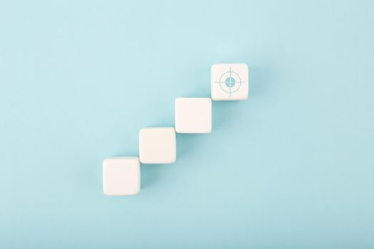 Ladder career, sales or business growth, success path or setting goal concept. White cubes as step stairs with target on bright blue background