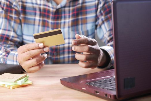 man hands holding credit card and using laptop shopping online .