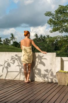 Young woman wearing towel relaxing near swimming pool at exotic location