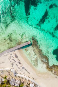 Aerial high top view of woman laying on wooden pier at sunny summer day in Cancun, Mexico, top view. Young sexy woman in red swimsuit in summertime in Caribbean. Summer beach vacation concept