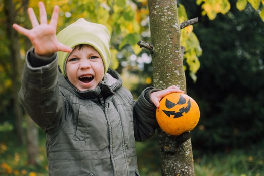 A boy with a Halloween pumpkin with eyes . The feast of fear. Halloween. An orange pumpkin with eyes. An article about Halloween.