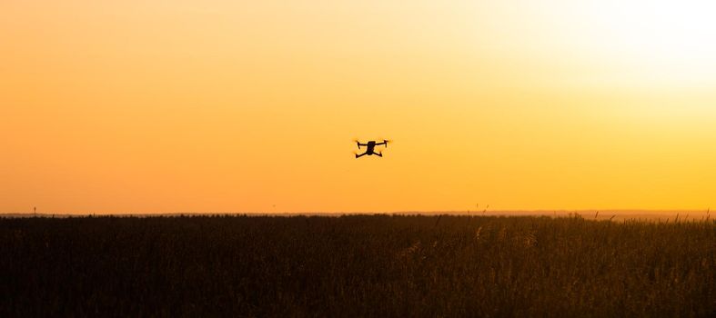 The drone is in flight at sunset . Video shooting from above. An article about the choice of a quadrocopter. Pros and cons of the drone. Sunset