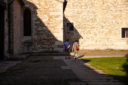 Aquileia, italy - August, 15: Couple of tourists walking next to the Basilica di Santa Maria Assunta on August 15, 2021