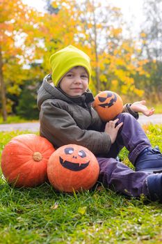 A boy with a Halloween pumpkin with eyes . The feast of fear. Halloween. An orange pumpkin with eyes. An article about Halloween.