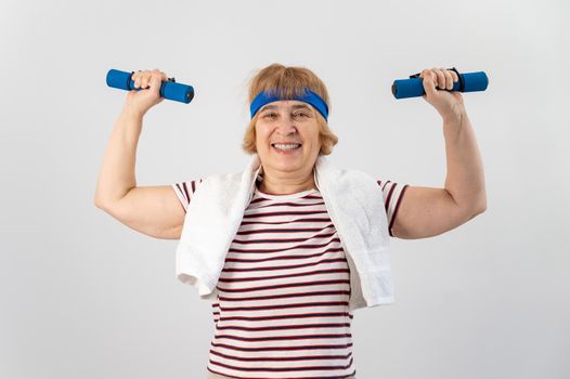 An elderly woman with a blue bandage on her head trains with dumbbells on a white background.