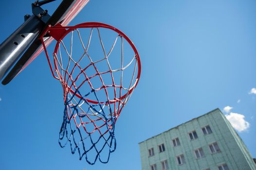 Bottom view of an empty basketball basket against the blue sky.