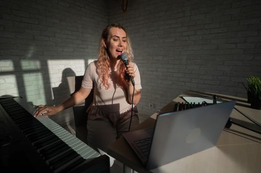 A female blogger sings and plays the live electronic piano. Portrait of a girl recording a song on a web camera and composing on a synthesizer. Online music lessons. Distance learning in quarantine