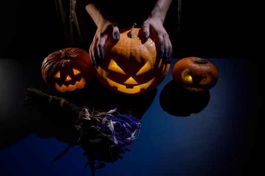 Close-up of female hands holding a halloween pumpkin in the dark.