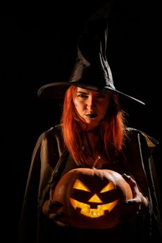 Wicked witch holding a jack-o-lantern for halloween.