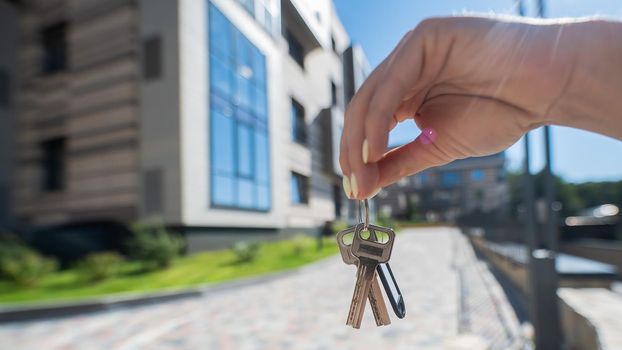 A woman holds the keys to a new house. Close-up of a female hand. Buying a property