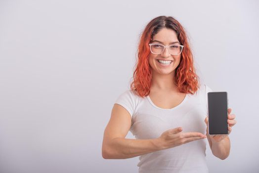 A Caucasian woman points to a smartphone with a blank screen on a white background.