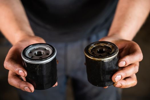 An auto mechanic holds a new and used oil filter