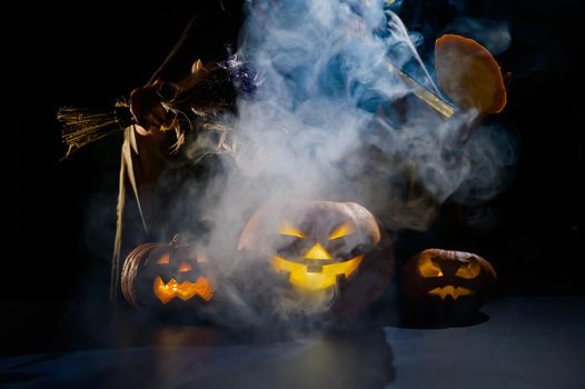 Witch casts a spell on a steaming pumpkin in the dark on Halloween.