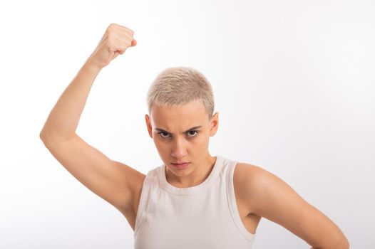 Young caucasian woman holding her fist up on a white background. A girl with short hair is fighting for rights.