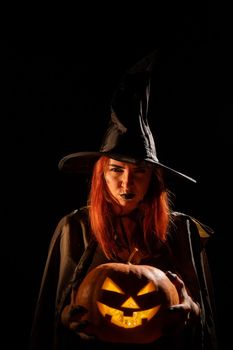 Wicked witch holding a jack-o-lantern for halloween.