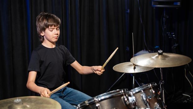 A boy plays drums in a recording studio.