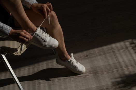 Woman put on new white leather sneakers.