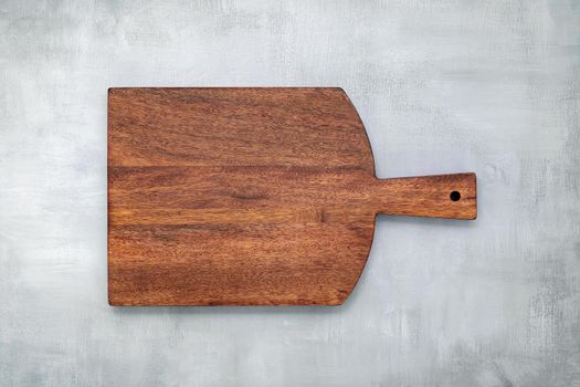 Empty vintage wooden cutting board set up on concrete background with copy space.