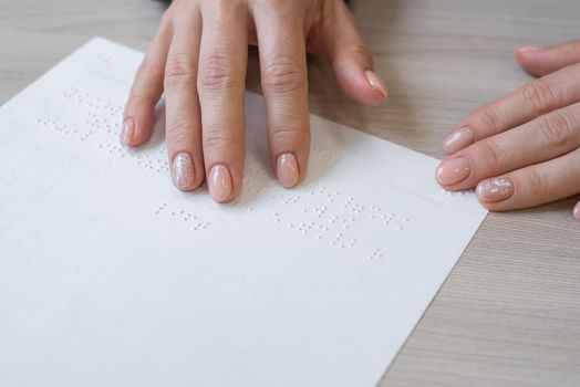 Close-up woman reads the text to the blind. Woman's hands on paper with braille code