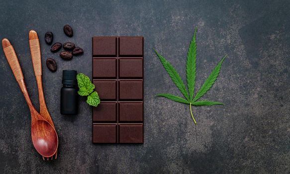 Food conceptual image of  cannabis leaf  with dark chocolate and fork on dark concrete background.