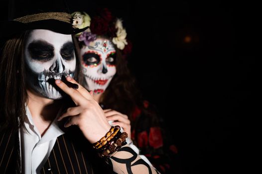 Man and woman in paired halloween costumes. Body art santa muerte and skeleton.