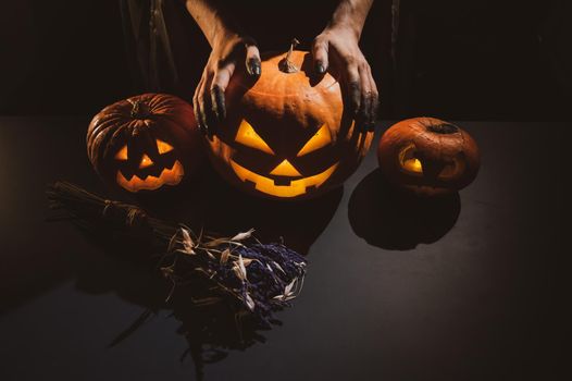 Close-up of female hands holding a halloween pumpkin in the dark.