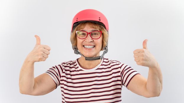 Elderly woman in ski helmet showing thumb up on white background