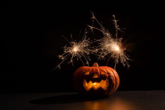 Halloween pumpkin with scary carved grimace and sparklers