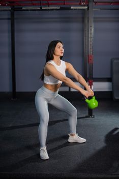 Asian woman doing exercises with dumbbells in the gym