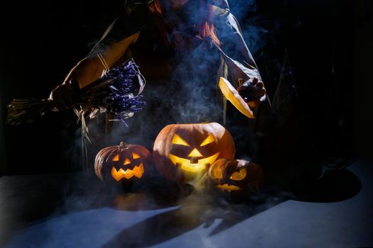 Witch casts a spell on a steaming pumpkin in the dark on Halloween.