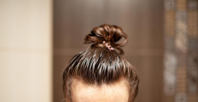 lifestyle woman paints henna gray hair, hair coloring self-care. Hair care at home. The woman applied a mask or balm to her hair.