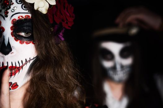 Woman in santa muerte costume and man in skeleton bodypainting for halloween