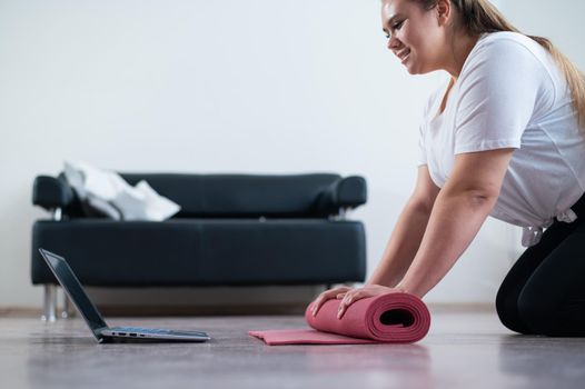 Young chubby woman preparing for an online fitness class. Distance training during the quarantine period.