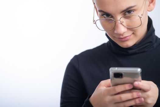 Young caucasian woman with short hair uses a smartphone on a white background