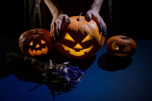 Close-up of female hands holding a halloween pumpkin in the dark.