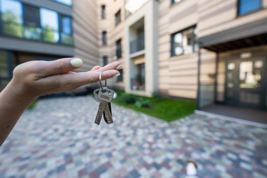 A woman holds the keys to a new house. Close-up of a female hand. Buying a property